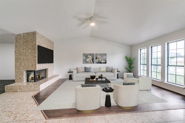 living room with wood-type flooring, lofted ceiling, ceiling fan, and a fireplace