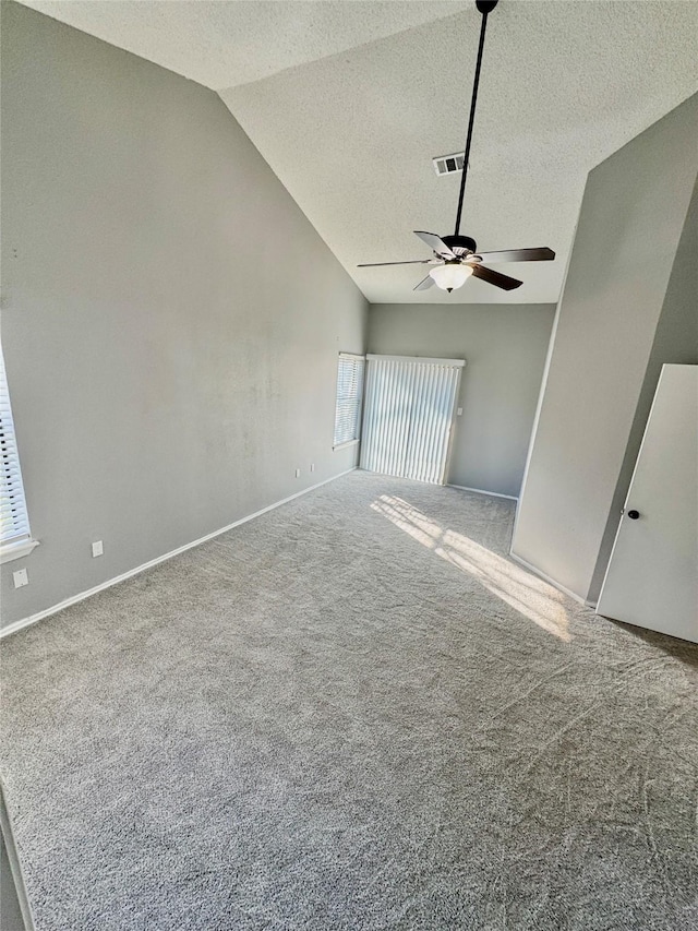 carpeted spare room featuring ceiling fan, vaulted ceiling, and a textured ceiling