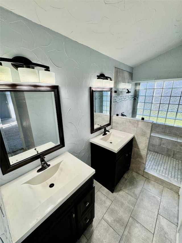 bathroom featuring vaulted ceiling, a tile shower, and vanity