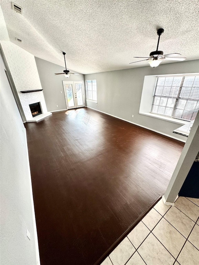 unfurnished living room featuring light hardwood / wood-style flooring, a fireplace, lofted ceiling, and ceiling fan