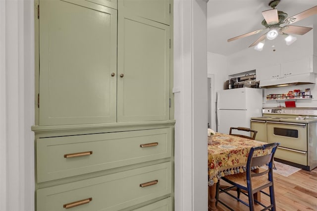 kitchen with light wood-type flooring, green cabinets, white fridge, ceiling fan, and stove