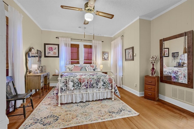 bedroom featuring crown molding, a textured ceiling, ceiling fan, and light hardwood / wood-style floors