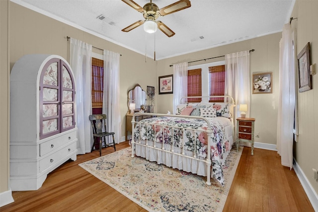 bedroom featuring crown molding, light hardwood / wood-style flooring, a textured ceiling, and ceiling fan