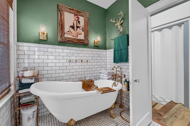 bathroom featuring wood-type flooring, a bathing tub, and tile walls