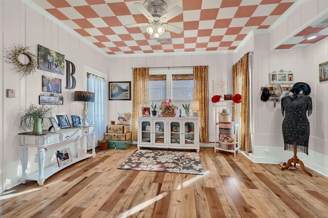 interior space with light hardwood / wood-style flooring, ornamental molding, wooden walls, and ceiling fan