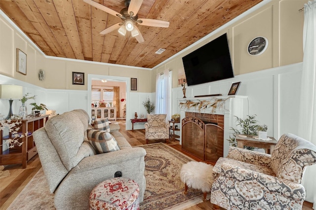 living room with ornamental molding, light hardwood / wood-style flooring, wooden ceiling, and ceiling fan