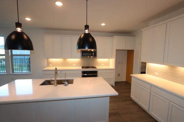 kitchen featuring decorative light fixtures, sink, a center island with sink, and black appliances