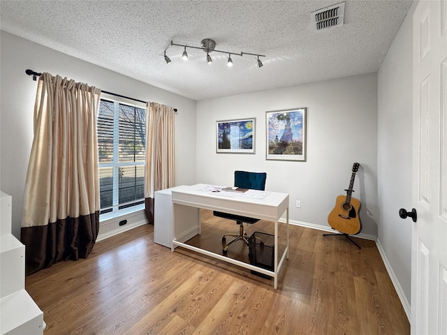 office featuring wood-type flooring, rail lighting, and a textured ceiling