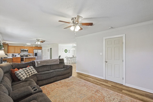 living room with ornamental molding, ceiling fan with notable chandelier, light hardwood / wood-style flooring, and a textured ceiling