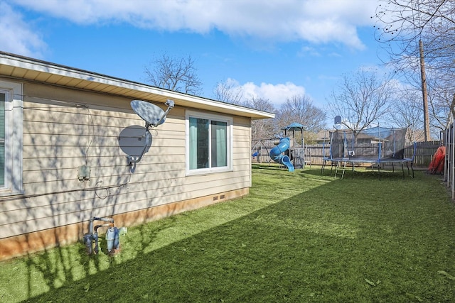 view of side of home featuring a playground, a yard, and a trampoline