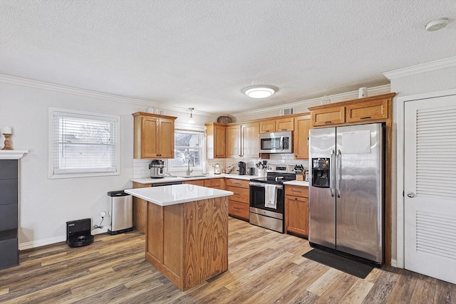 kitchen with a center island, ornamental molding, stainless steel appliances, light hardwood / wood-style floors, and backsplash