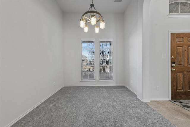 unfurnished dining area featuring carpet flooring and an inviting chandelier