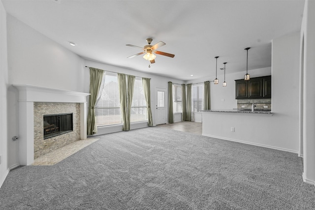 unfurnished living room with a premium fireplace, light carpet, and ceiling fan