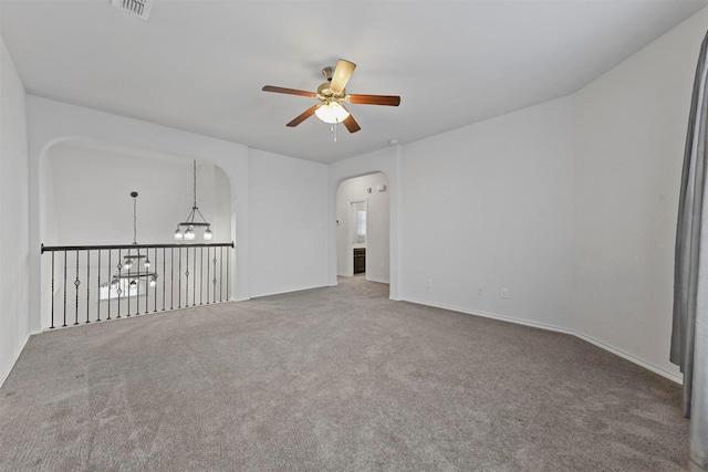 empty room featuring ceiling fan with notable chandelier and carpet floors