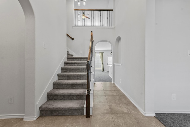 staircase with tile patterned flooring and a high ceiling