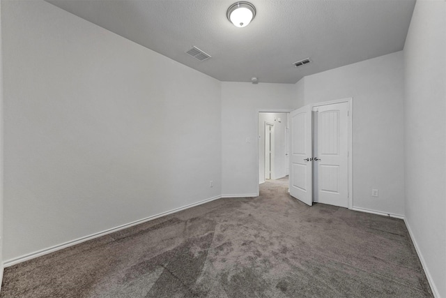 carpeted empty room featuring a textured ceiling