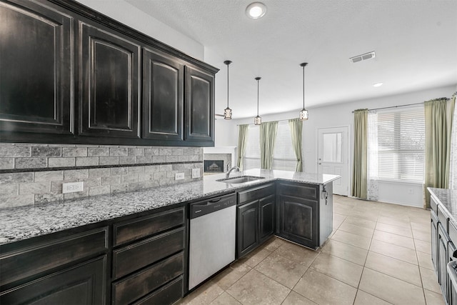 kitchen featuring pendant lighting, tasteful backsplash, sink, stainless steel dishwasher, and light tile patterned floors