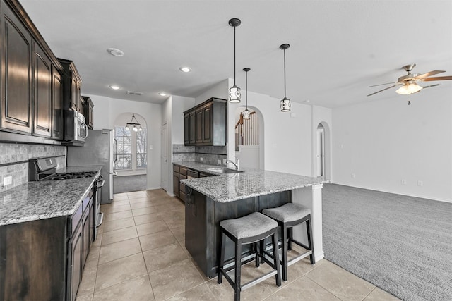 kitchen featuring pendant lighting, light tile patterned floors, stainless steel appliances, tasteful backsplash, and light stone counters