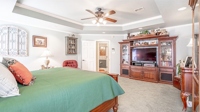 carpeted bedroom with ornamental molding, ensuite bath, ceiling fan, and a tray ceiling