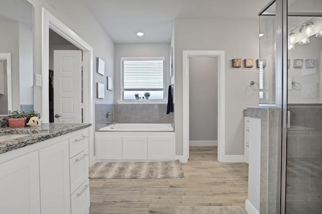 bathroom featuring hardwood / wood-style flooring, vanity, and shower with separate bathtub