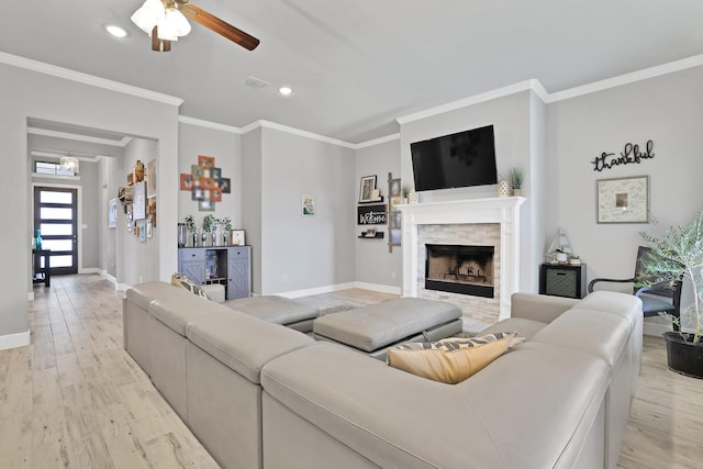 living room with a fireplace, ornamental molding, light hardwood / wood-style floors, and ceiling fan