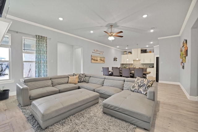 living room with crown molding, ceiling fan, and light hardwood / wood-style floors