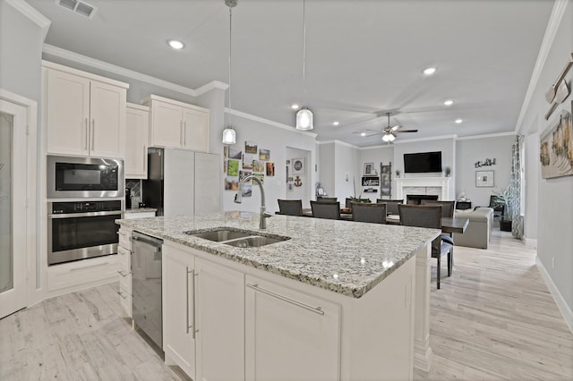 kitchen featuring appliances with stainless steel finishes, sink, white cabinets, hanging light fixtures, and a center island with sink