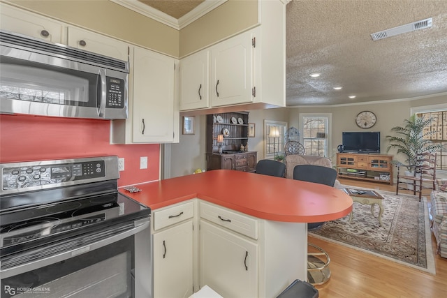 kitchen featuring white cabinetry, kitchen peninsula, stainless steel appliances, crown molding, and a textured ceiling