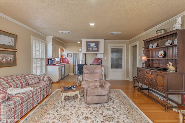 living room featuring ornamental molding, a textured ceiling, and light wood-type flooring