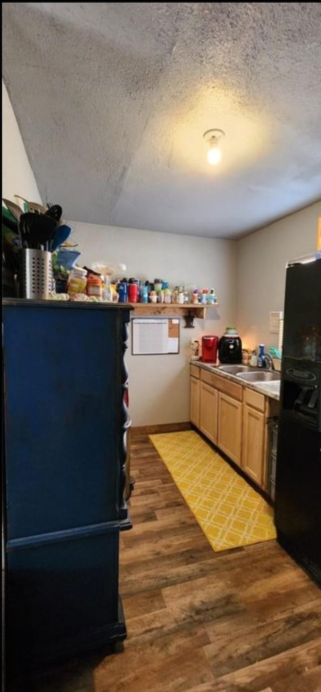 kitchen with black fridge, a textured ceiling, and dark hardwood / wood-style flooring