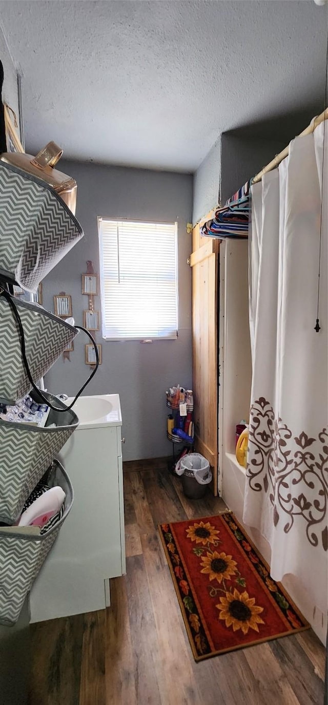 laundry area with dark wood-type flooring, sink, and a textured ceiling