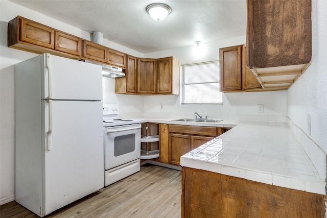 kitchen with sink, tile countertops, white appliances, and light wood-type flooring