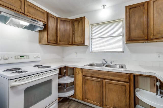 kitchen with sink, dark wood-type flooring, tile counters, and electric stove