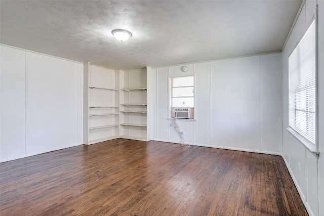 unfurnished room with dark hardwood / wood-style floors, cooling unit, a textured ceiling, and built in shelves