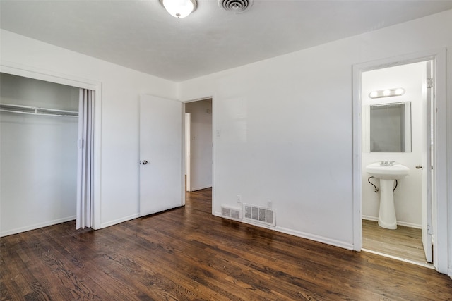 unfurnished bedroom with dark wood-type flooring, ensuite bath, and a closet