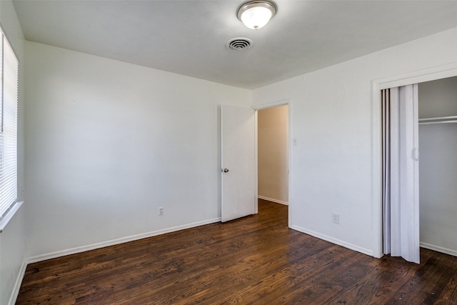 unfurnished bedroom featuring a closet and dark hardwood / wood-style floors