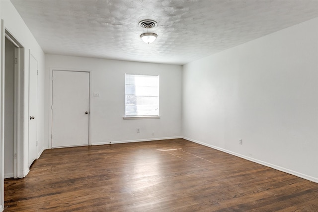 unfurnished room with a textured ceiling and dark hardwood / wood-style flooring