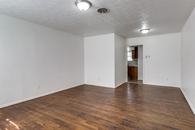 empty room featuring dark hardwood / wood-style floors and a textured ceiling