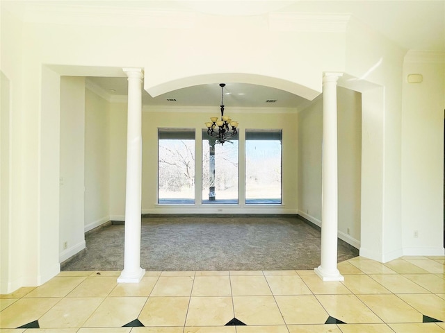 carpeted empty room with crown molding, decorative columns, and a chandelier