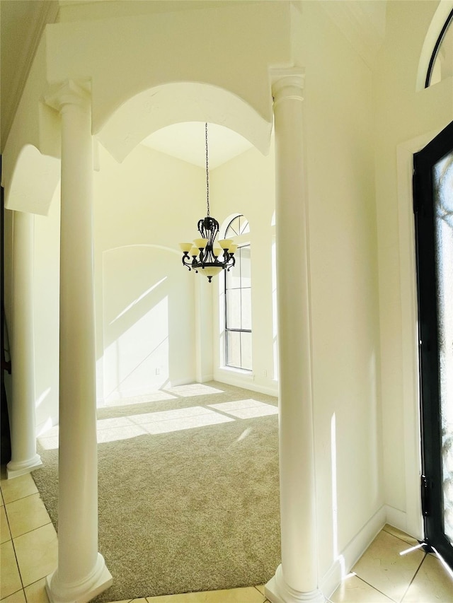 interior space featuring an inviting chandelier, light colored carpet, and ornate columns