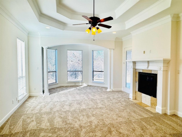 unfurnished living room with ornate columns, light carpet, and a tray ceiling