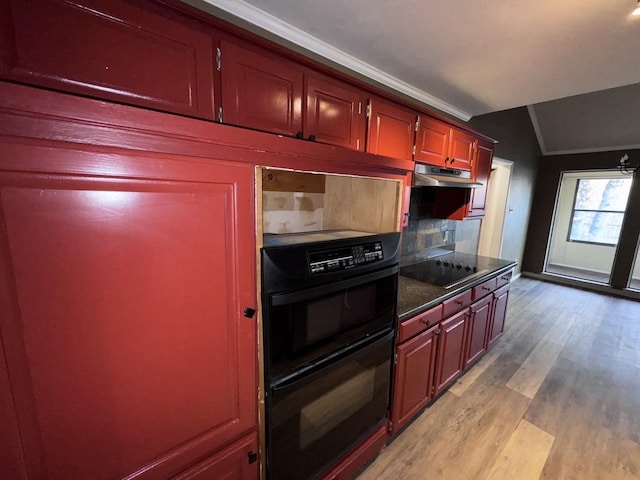 kitchen featuring light hardwood / wood-style flooring, vaulted ceiling, decorative backsplash, and black appliances