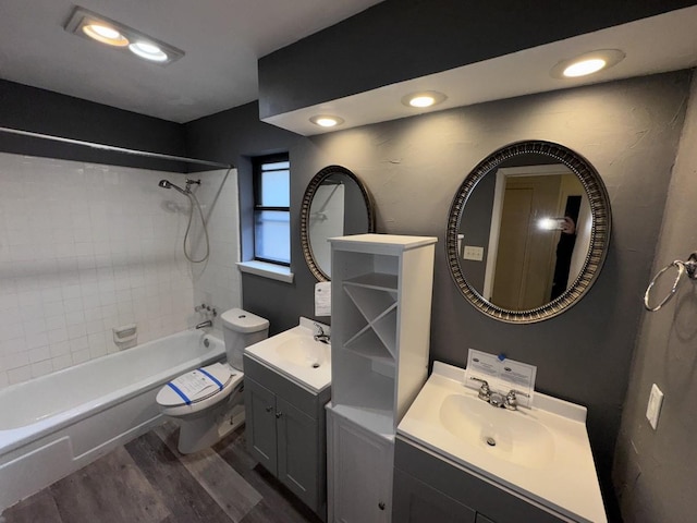 full bathroom with vanity, hardwood / wood-style floors, tiled shower / bath combo, and toilet