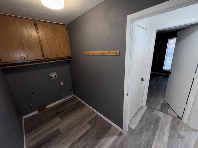 clothes washing area with washer hookup, light hardwood / wood-style floors, and cabinets