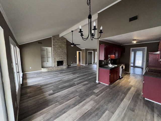 kitchen with sink, dishwasher, vaulted ceiling with beams, a fireplace, and ceiling fan with notable chandelier