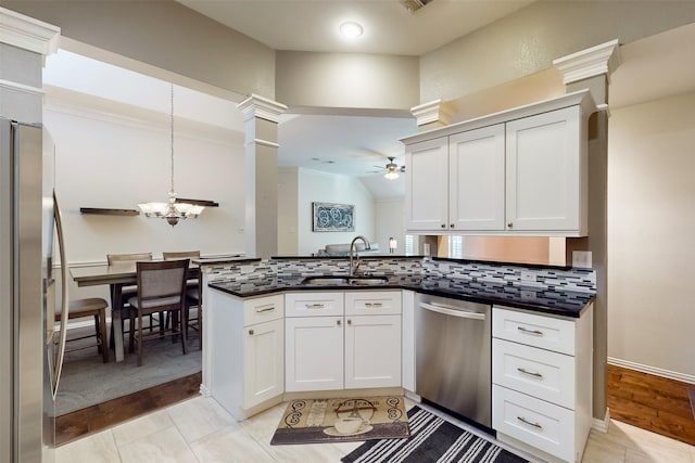 kitchen featuring pendant lighting, sink, white cabinetry, stainless steel appliances, and tasteful backsplash