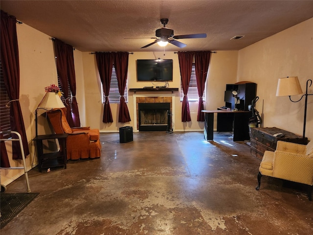 living room featuring a tiled fireplace, ceiling fan, and a textured ceiling