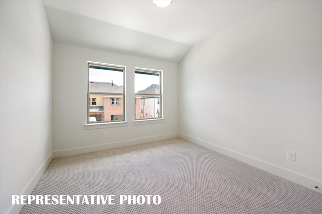 spare room with lofted ceiling and light carpet