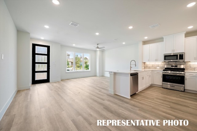 kitchen featuring white cabinetry, appliances with stainless steel finishes, kitchen peninsula, and light hardwood / wood-style floors