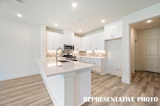 kitchen featuring sink, light hardwood / wood-style flooring, appliances with stainless steel finishes, backsplash, and white cabinets